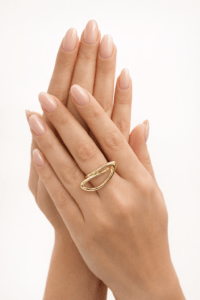 Altın renk modern tasarım yüzük takılı, nude ton manikürlü zarif kadın eli – e-ticaret takı ürün fotoğrafı