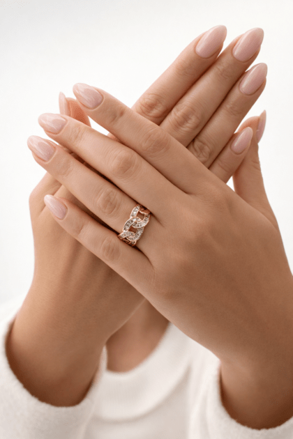 Zirkon taş detaylı VIP zincir tasarımlı gold yüzük, nude pembe manikürlü elde stüdyo çekimi